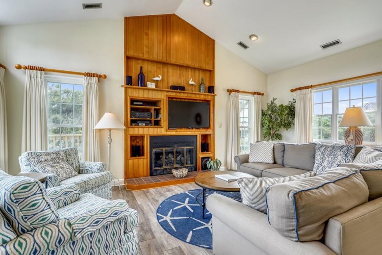 Gather in this inviting living space with plush seating, a warm fireplace, and sunlit windows framing serene views—your perfect spot to relax and reconnect.