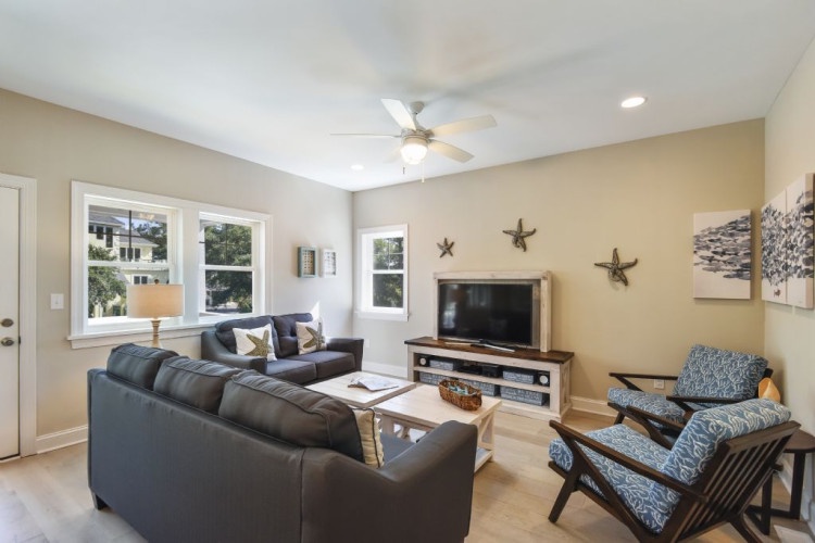 Unwind in your bright living room featuring plush seating, coastal decor touches, and entertainment at your fingertips—perfect for cozy evenings after exploring.