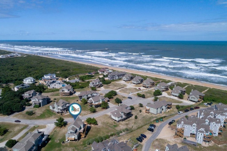 A coastal neighborhood nestled between lush greenery and pristine sandy shores, offering direct beach access and serene oceanfront living with rolling waves visible in the distance.
