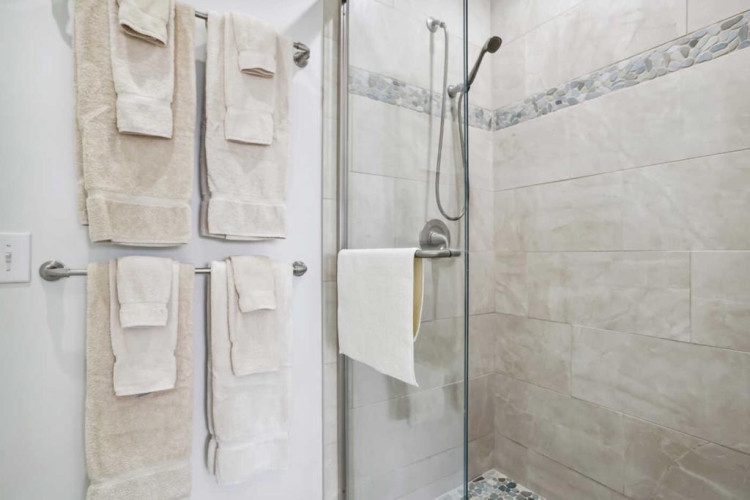 Step into your private spa-like retreat with a spacious walk-in shower, elegant tile work, and plush towels ready for your arrival.