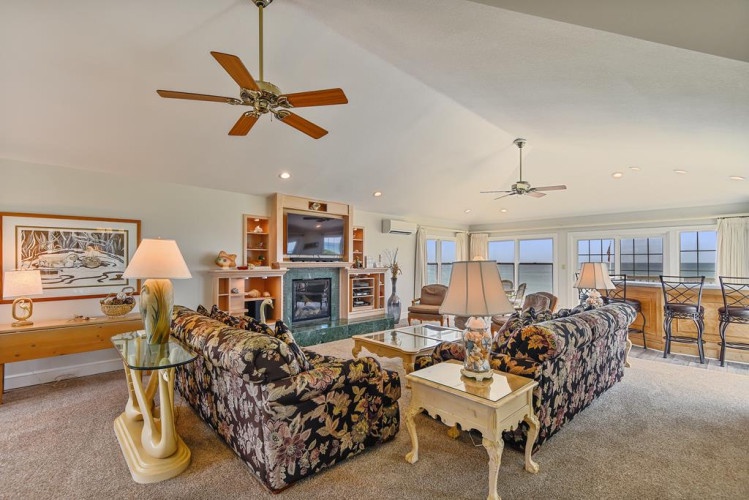 Kick back in your bright, spacious living room with ocean views through expansive windows. Sink into comfy seating, enjoy the fireplace ambiance, and step out to your private balcony.