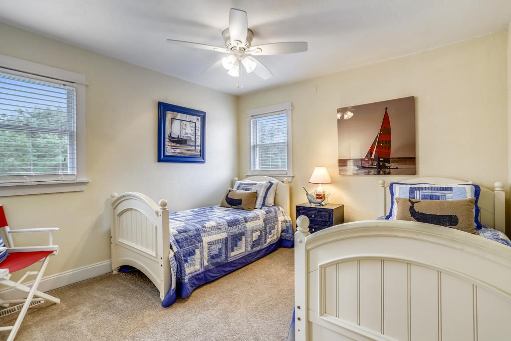 Your coastal-themed bedroom awaits with twin beds dressed in nautical blue, crisp white furnishings, and cheerful natural light—perfect for peaceful nights and bright mornings.