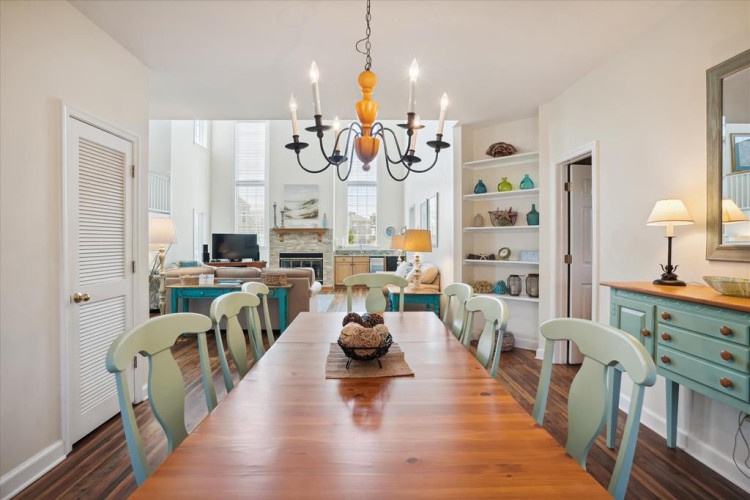 Gather around this charming dining table, where coastal elegance meets comfort under a statement chandelier. Natural light fills the open space, inviting you to enjoy meals with loved ones.