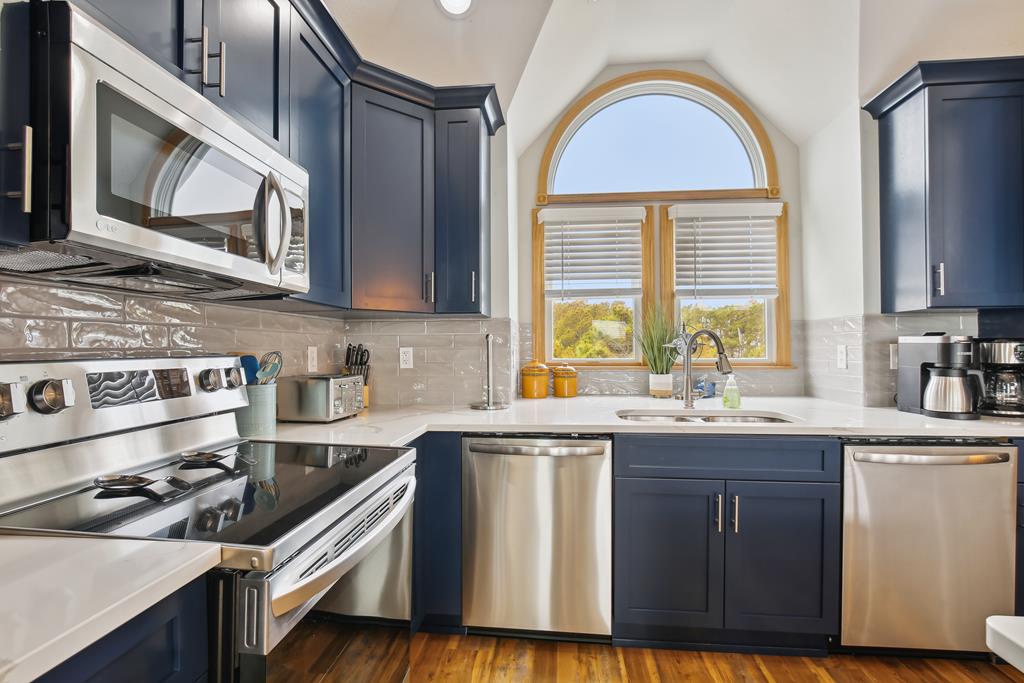 Your fully equipped kitchen features stainless steel appliances, stylish navy cabinetry, and a charming arched window that fills the space with natural light—perfect for preparing meals during your stay.