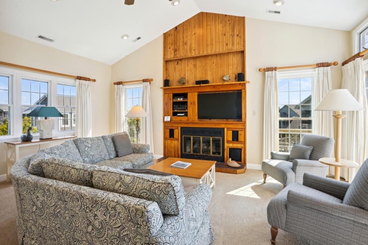Relax in your bright, airy living room with soaring ceilings, a cozy fireplace, and large windows framing peaceful neighborhood views. Unwind on plush seating as natural light fills the space.