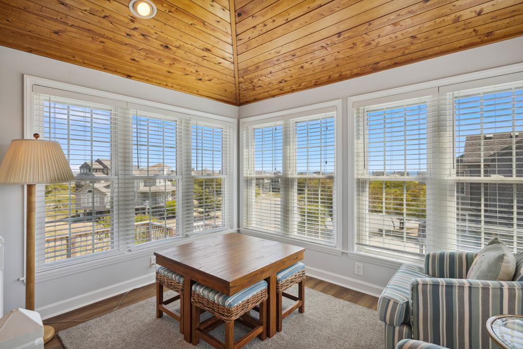 You'll love the warmth of the vaulted wooden ceiling above your cozy seating area, where sunlight streams through tall windows overlooking the neighborhood. Perfect for morning coffee or evening relaxation.
