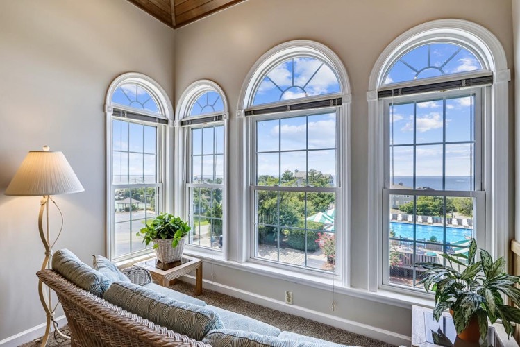 Relax in your private sunlit haven with stunning arched windows framing sweeping views of the pool, ocean, and lush greenery—a perfect retreat for unwinding in comfort and style.