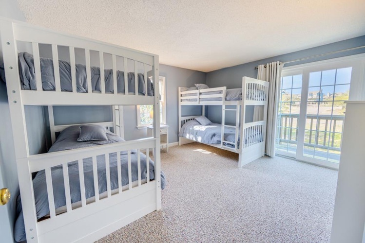 Bright, spacious room with two sturdy bunk beds perfect for families or groups. Natural light pours through large glass doors leading to your private balcony with scenic views.