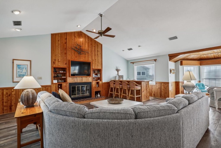 Step into a spacious open-concept retreat where a cozy fireplace, stylish wood accents, and a plush sectional invite you to unwind. Enjoy your morning coffee at the kitchen bar or relax under vaulted ceilings.