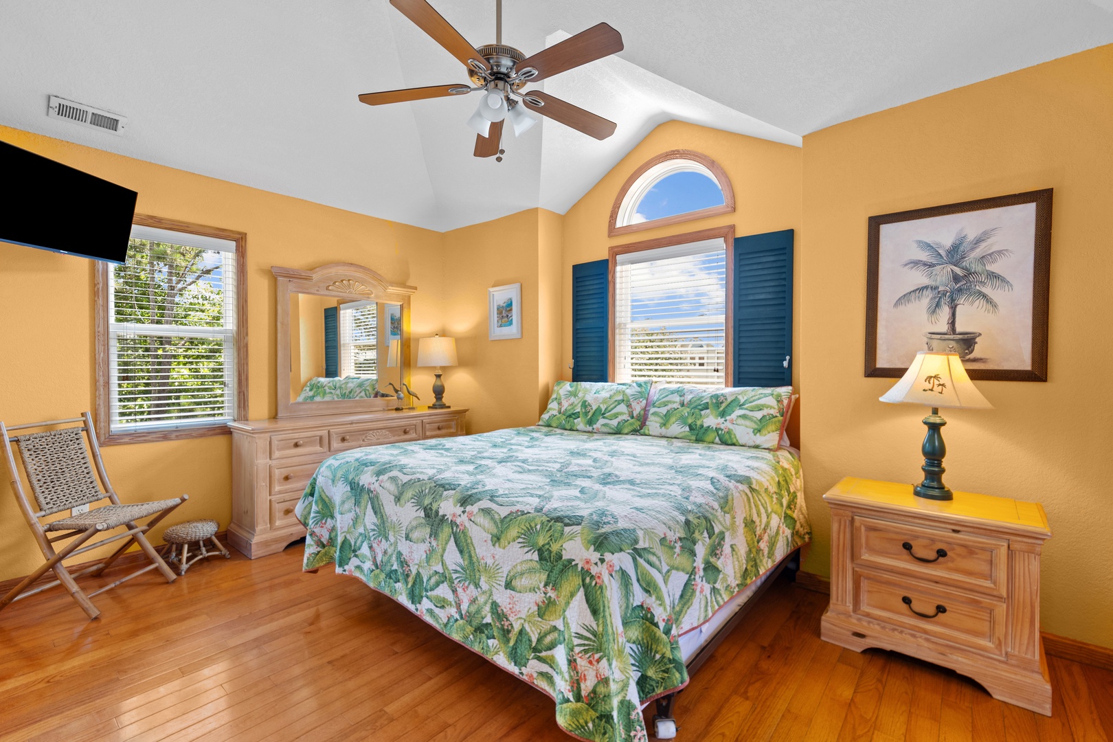 Your cheerful bedroom retreat features a plush bed draped in tropical linens, elegant wood furnishings, and vaulted ceilings with a ceiling fan to keep you cool and comfortable throughout your stay.