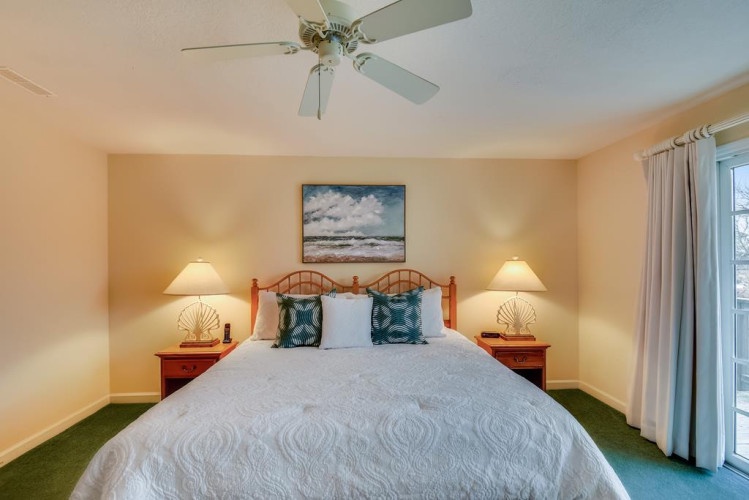 Unwind in your cozy bedroom featuring a plush bed, gentle ceiling fan, and beach-themed décor that sets the tone for a restful coastal getaway.