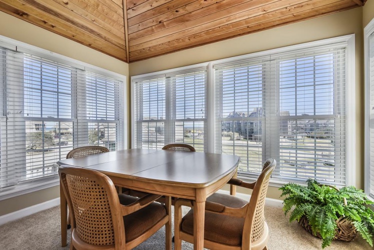 Gather around this inviting dining table, where warm wood tones meet natural light streaming through expansive windows. The vaulted wood ceiling adds rustic charm to your meals together.