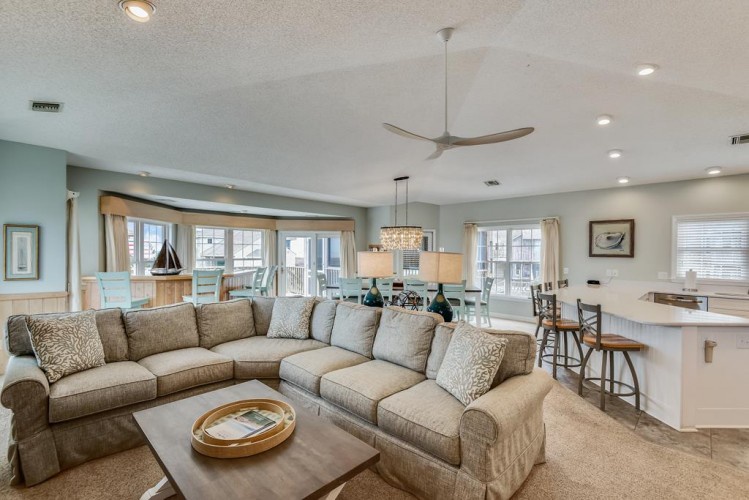 Stretch out on the plush sectional in your spacious open-concept living area, where coastal charm meets modern comfort—perfect for relaxing or gathering with loved ones.