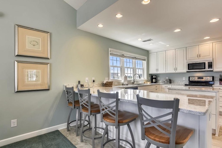 You'll love gathering at this open breakfast bar, perfect for morning coffee or casual meals. The bright, airy kitchen offers coastal charm and everything you need to feel at home.