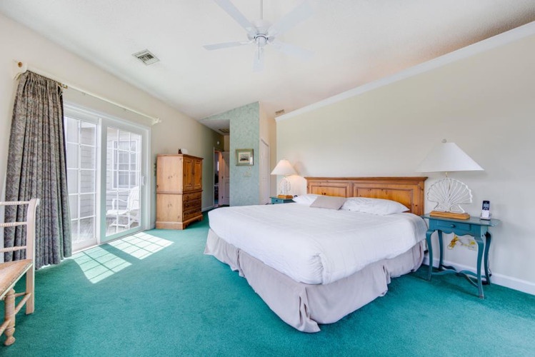 Unwind in your sun-drenched bedroom, where soft carpeting, coastal-inspired décor, and a plush bed await your peaceful retreat. French doors open onto your private outdoor space.