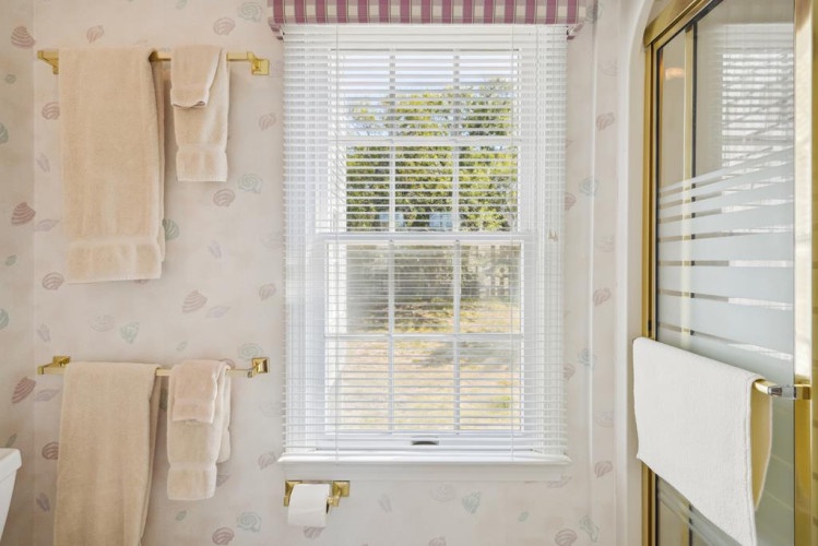 Bright natural light fills your bathroom through lovely windows, casting a warm glow on the soft towels waiting for you after a relaxing bath or shower.