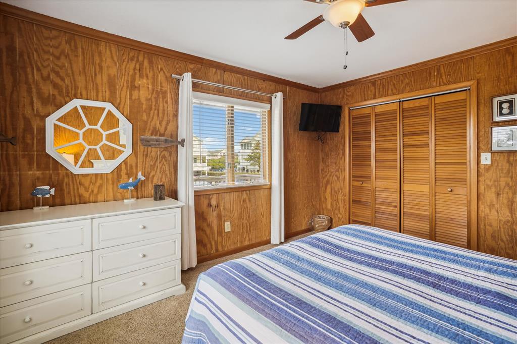 Relax in your cozy bedroom with warm wood-paneled walls, ceiling fan, flat-screen TV, and plenty of closet space for unpacking.