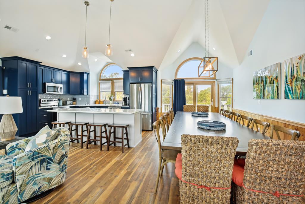 Sunlight pours through soaring arched windows, illuminating your open-concept kitchen and dining space. Gather around the island or long dining table, perfect for meals and memories together.