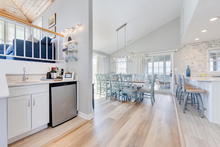Your coastal retreat flows seamlessly from kitchen to dining, bathed in natural light and wrapped in soft blues and whites—a perfect space for gathering over meals and ocean breezes.