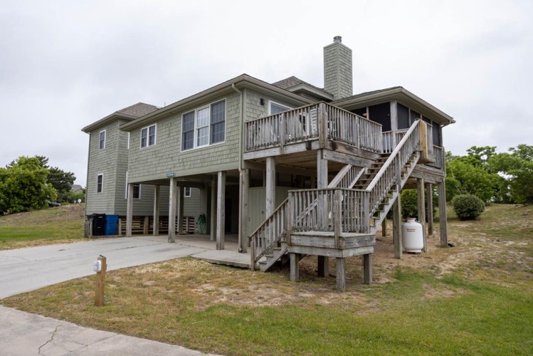 Elevated beach house design with multiple outdoor decks, offering coastal charm and natural surroundings within close proximity to the shore.