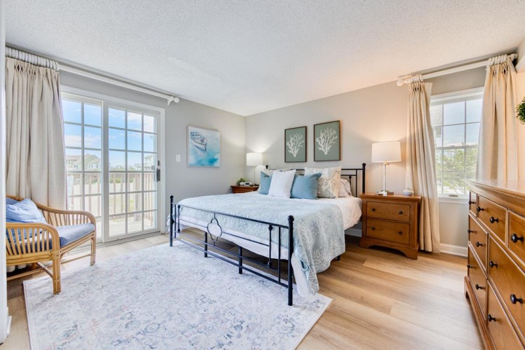 Your serene bedroom retreat awaits, featuring a plush bed, natural light streaming through French doors, and a cozy reading chair—perfect for unwinding after a day of adventure.