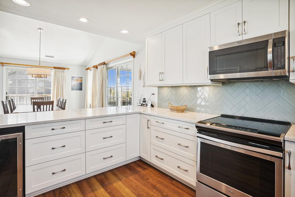 Your fully-equipped kitchen gleams with white cabinetry and modern stainless appliances, offering everything you need to create meals together. The open layout flows into the dining area, perfect for morning coffee or vacation dinners.