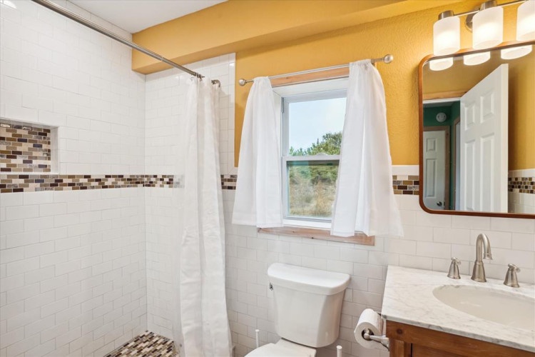 Your bright bathroom features a refreshing shower, stylish tile accents, and a window view that brings natural light and the outdoors into your space.