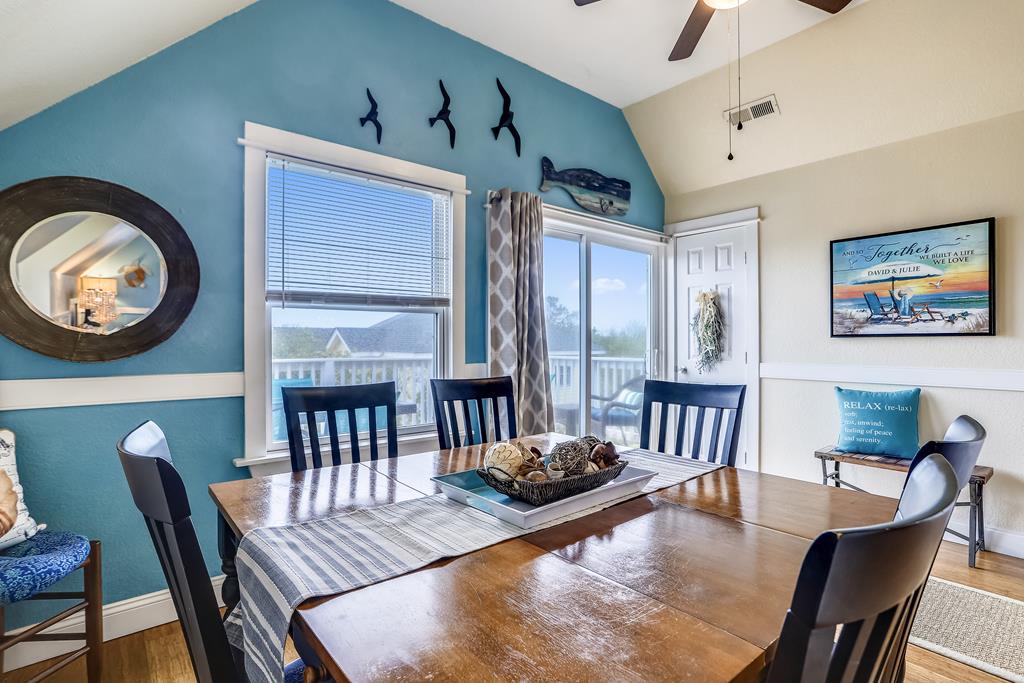 Gather around this welcoming dining table with coastal charm, where ocean-themed decor and natural light set the perfect scene for your vacation meals together.