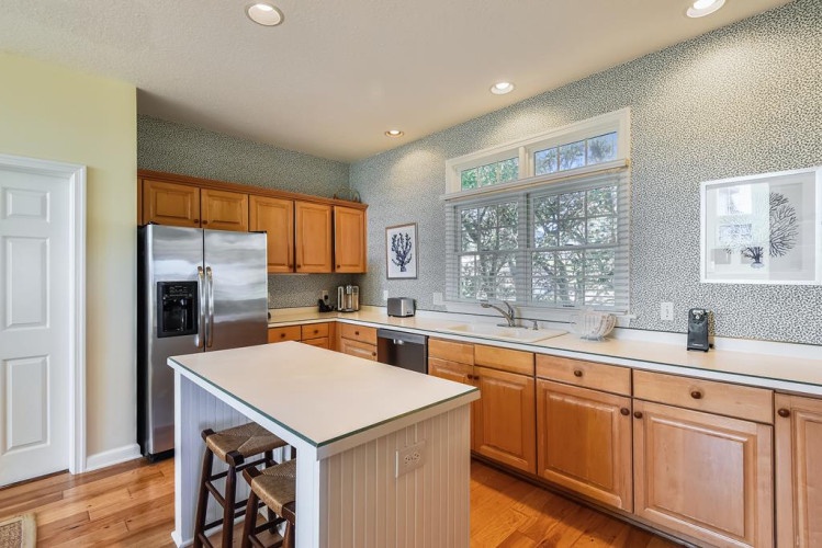 Your inviting kitchen awaits with stainless appliances, spacious counters, and natural light streaming through the window—perfect for preparing meals or enjoying morning coffee at the island.