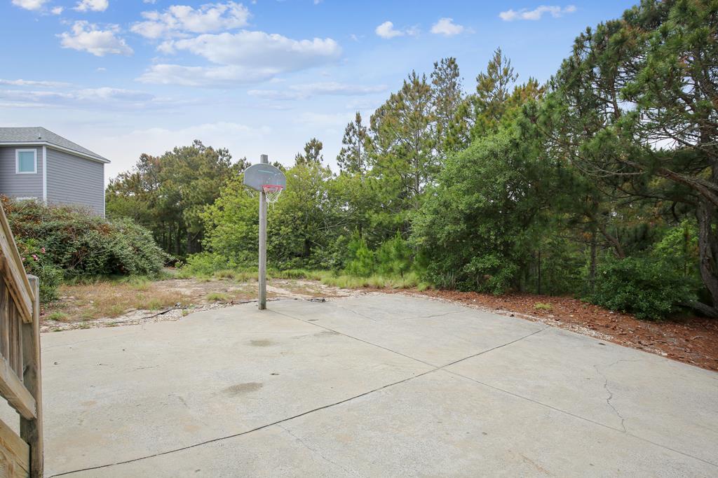 The property features an outdoor basketball court surrounded by mature trees and natural landscaping, providing recreational space in a peaceful wooded setting.