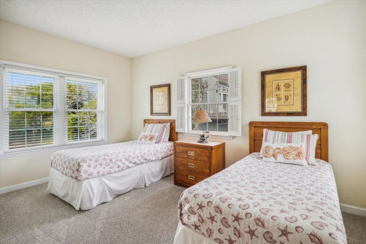 Bright and airy twin bedroom with natural light streaming through large windows, inviting decor, and plenty of space for you to unwind. Perfect for friends or family sharing your getaway.