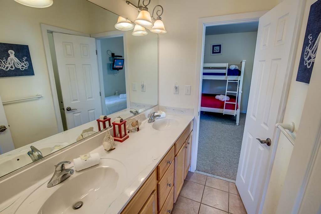 Freshen up in your spacious bathroom with double sinks, perfect for families sharing this coastal retreat. The nautical decor and convenient bunk room access make morning routines effortless.