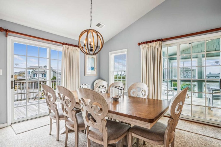 Gather around the elegant dining table where you'll savor meals together beneath a striking orb chandelier. Soft natural light streams through expansive windows, offering views of the surrounding neighborhood.