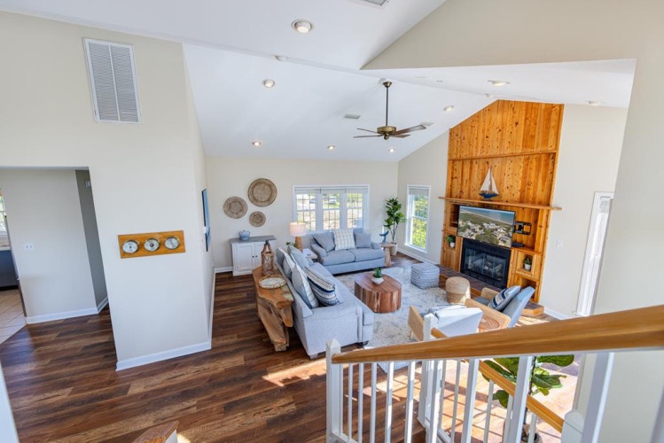 Step into your spacious living room where vaulted ceilings, rich hardwood floors, and a warm wood-paneled fireplace create the perfect setting for cozy evenings with loved ones.