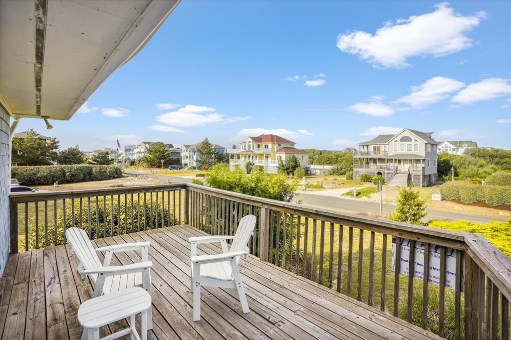 Settle into these deck chairs and soak in peaceful views of lush greenery and colorful coastal homes under a bright, open sky—your perfect spot for morning coffee or evening relaxation.