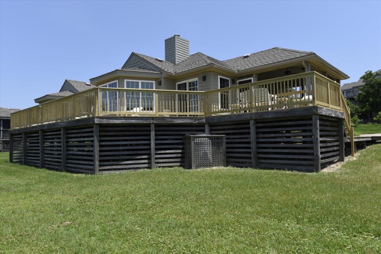 A spacious waterfront vacation home with a wraparound deck overlooking the surrounding area, blending comfort with scenic location on the shoreline.