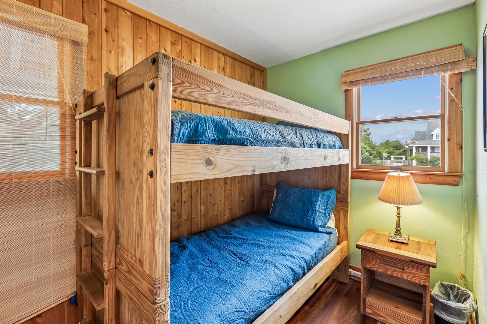 Cozy bunk room with rustic wood accents and cheerful blue bedding, perfect for your little adventurers. Natural light pours through the window, brightening this welcoming space for restful nights.