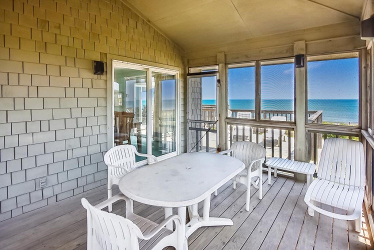 Picture yourself savoring morning coffee on your private covered porch, white Adirondack chairs framing stunning turquoise waters just steps away—your beachfront retreat awaits.