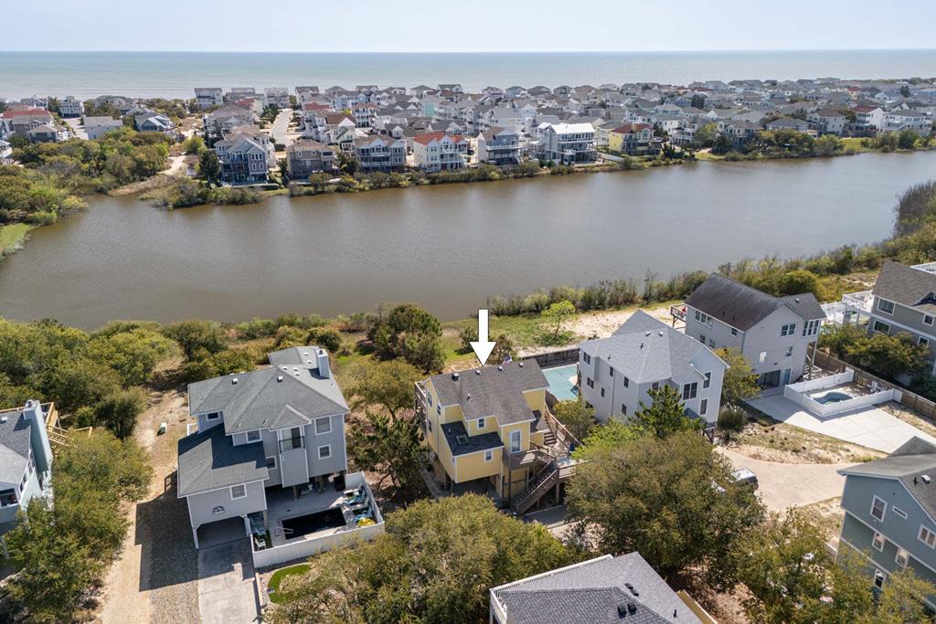 Coastal retreat nestled between serene bay waters and the ocean, part of a charming beach community offering peaceful waterfront access.