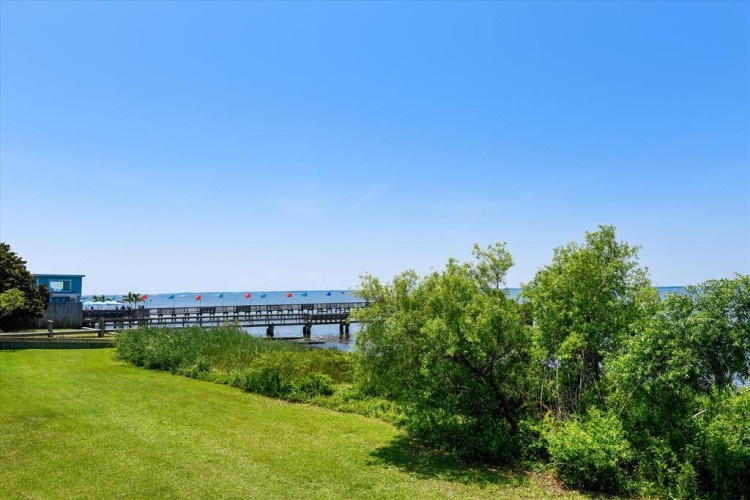 The property is situated near a scenic waterfront area with a walking pier and lush greenery—an inviting backdrop for your coastal getaway.
