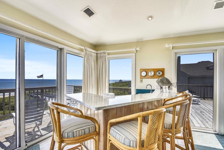 Imagine starting your mornings at this sunlit dining table, coffee in hand, with endless ocean views stretching before you and direct deck access for easy beach days.