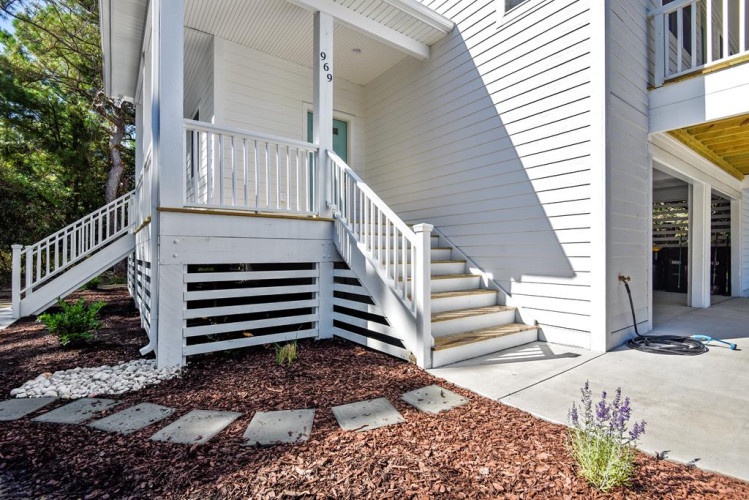 Bright, welcoming exterior featuring a freshly painted white facade with easy access stairways and landscaped pathways leading to your vacation retreat.