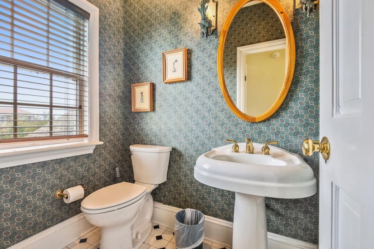 Charming vintage-inspired bathroom with patterned wallpaper, pedestal sink, and natural light to refresh you during your stay.