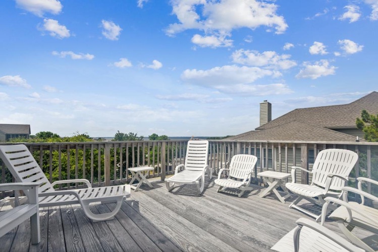 A spacious rooftop deck offers plenty of white lounge chairs where you can unwind, soak up the sun, and take in peaceful views of the surrounding treetops and water.