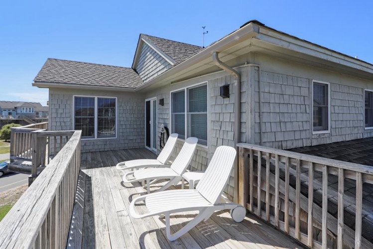 Charming coastal retreat with weathered shingle siding and expansive deck, offering a peaceful spot to soak in ocean breezes and neighborhood views during your stay.