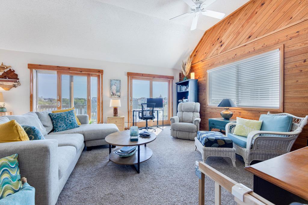 Settle into a coastal-inspired living space with vaulted wood ceilings, comfortable seating, and lake views framed by large windows—your perfect spot to unwind after a day of adventure.