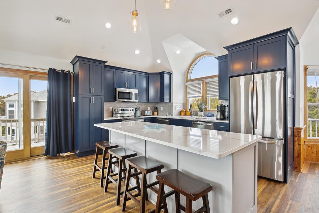 Your spacious kitchen features gleaming countertops, stainless steel appliances, and a large island with seating, perfect for preparing meals or gathering with loved ones in natural light.