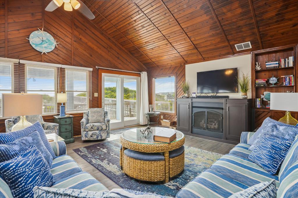 Unwind in your cozy living room with vaulted wood ceilings, comfortable seating, and a warm fireplace—perfect for relaxing after a day of exploring the coast.