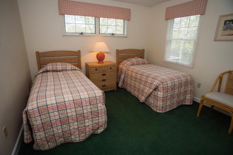 Settle into your cozy twin bedroom with plaid bedding, warm lighting, and peaceful garden views—perfect for restful nights after exploring the area.