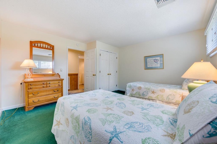 Your coastal-themed twin bedroom features cheerful sea turtle and starfish prints, classic wood furnishings, soft lighting, and ample closet space for unpacking and settling in comfortably.